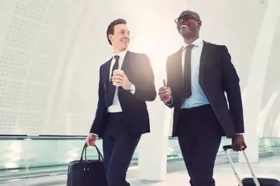 Two Businessmen Laughing Together While Walking Through an Airport Terminal Two businessmen laughing together while walking through an airport terminal, representing a positive and enjoyable travel experience