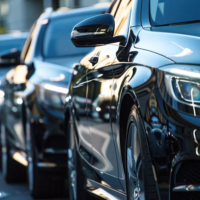 Black luxury sedan cars standing in a row on a wet surface, representing a premium car fleet.